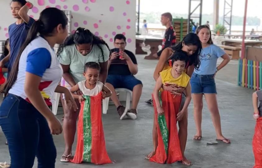 Crianças e adolesCrianças participam da corrida do saco durante a Colônia de Fériascentes durante atividade esportiva